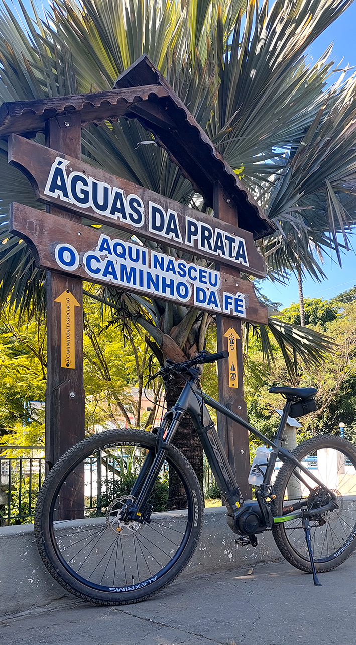 Bike elétrica em frente à placa do Caminho da Fé em Águas da Prata