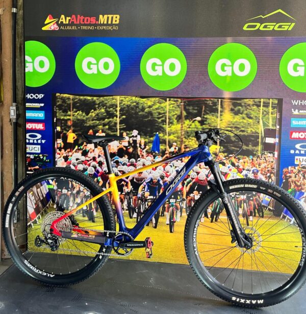 Bicicleta OGGI Agile Sport em frente ao painel da ArAltos MTB