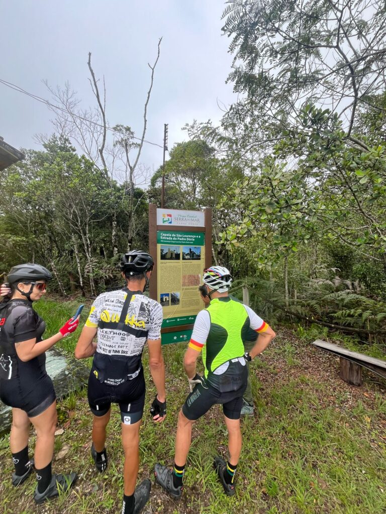 Ciclistas leem uma placa de informação durante expedições de mountain bike 