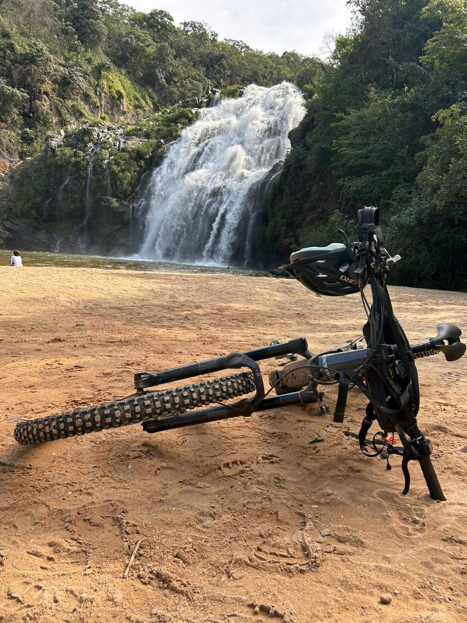 Bike deitada no chão em frente à cachoeira durante expedições de mountain bike ArAltos MTB